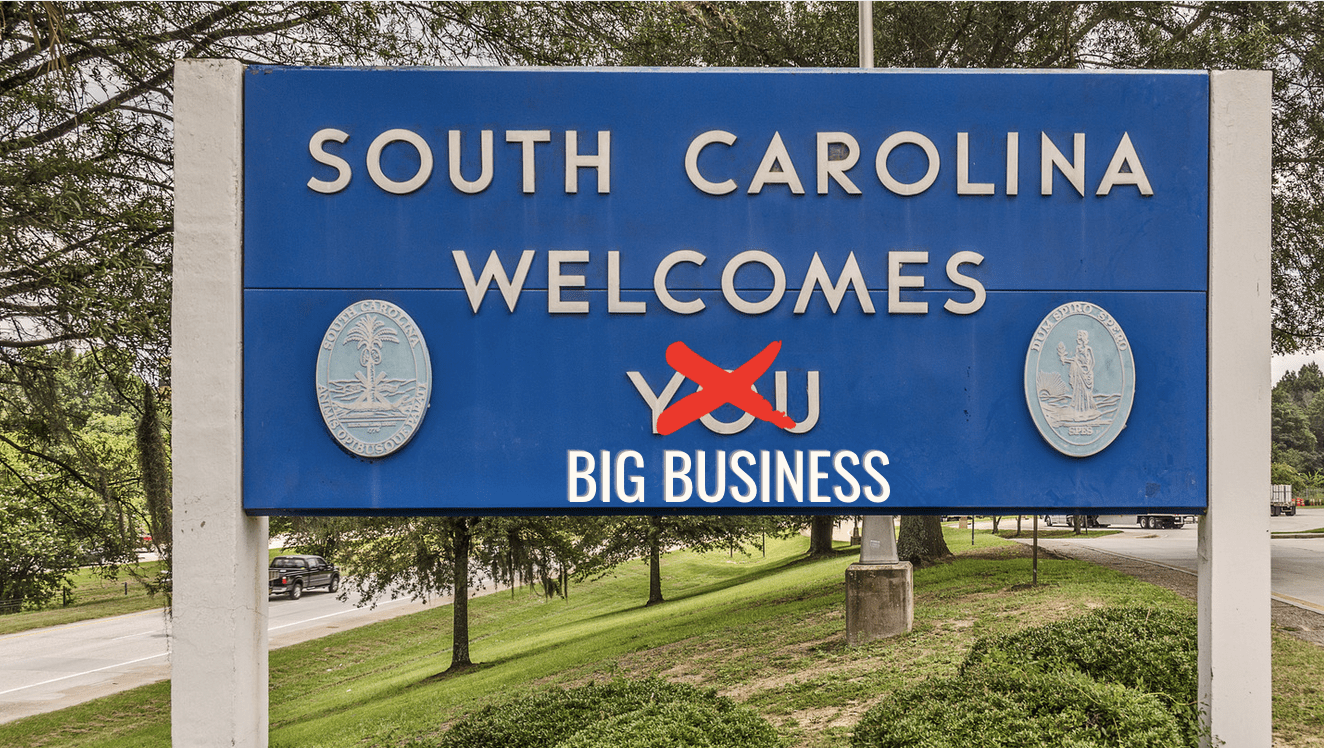 Image of a sign that says "South Carolina Welcomes You" except "You" is crossed out and instead it says "Big Business." 